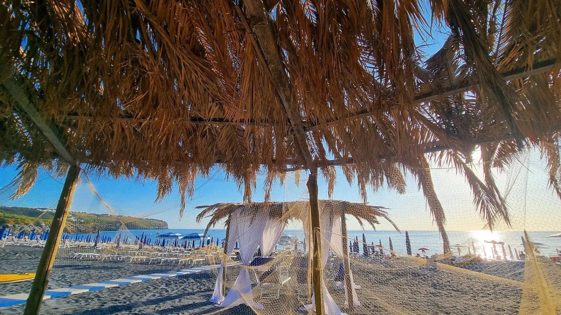 Il Lido Azzurro visto da sotto la pergola di palme, con la baia di San Nicola Arcella